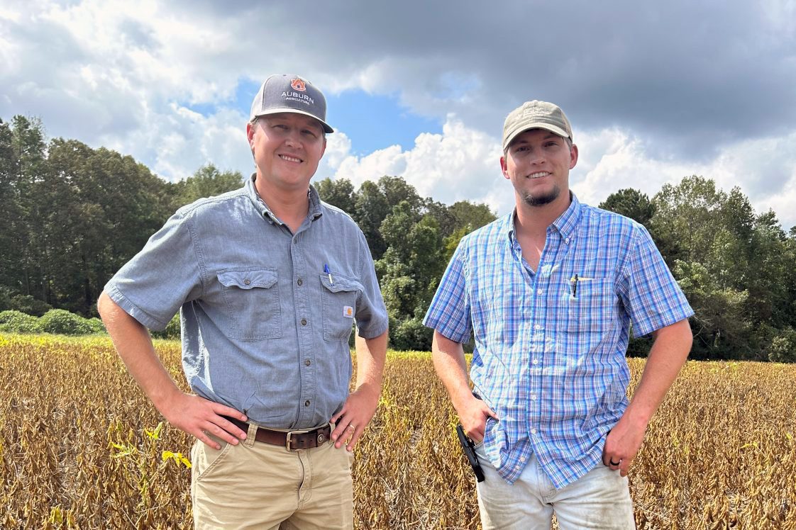 Farmer Payton Key and Extension Agronomic Crops Agent Cade Grace posing for a picture in a soybean field.