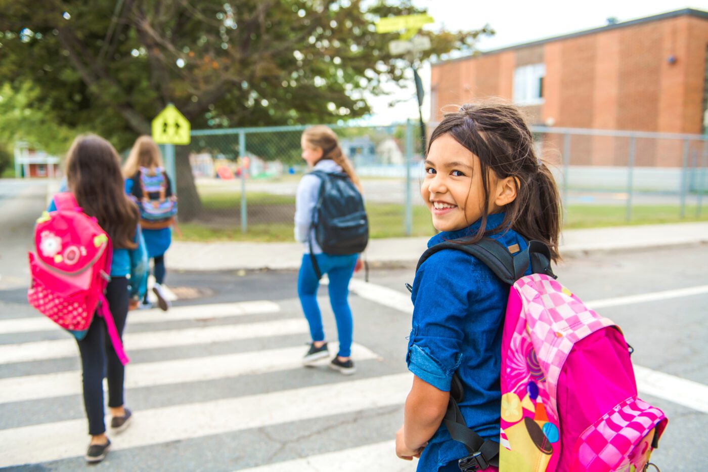 A smiling school girl walking in a crosswalk.