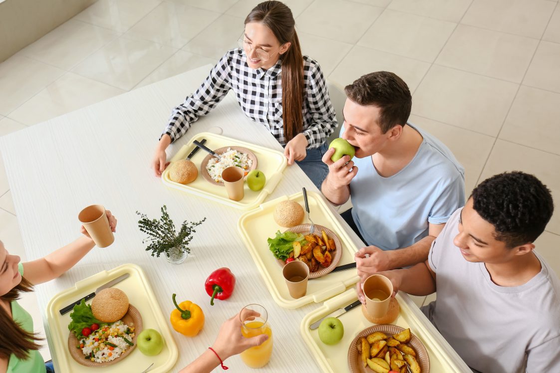 Students who are high school age enjoying a healthy lunch in a cafeteria.