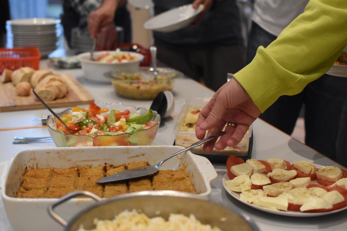 A kitchen counter covered with dishes for a pot luck meal.