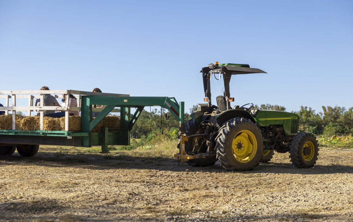 A tractor in a field pulling a wagon trailer. Used for article about how to prevent farm equipment theft.