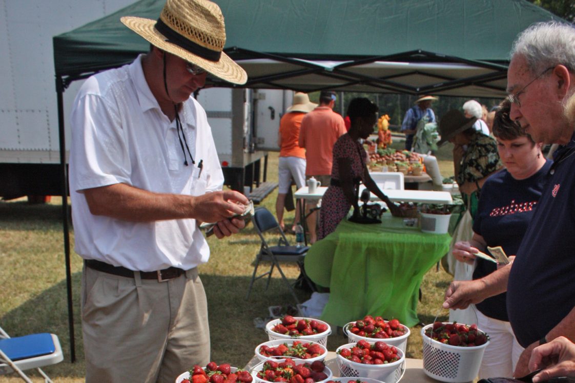 A man selling strawberries at a farmers market.