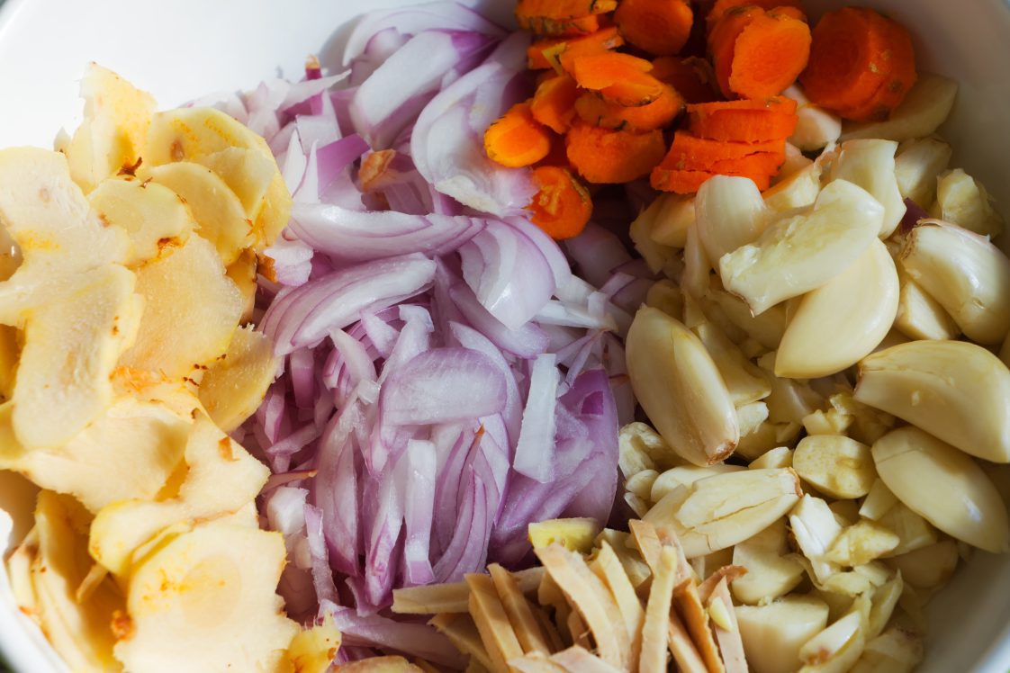 Close-up shot of cut fresh turmeric, onion, ginger, galangal and garlic inside bowl. Ingredient for making Chili paste or 'Sambal Cili'
