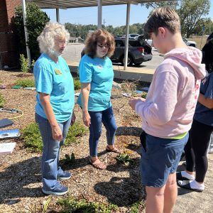 Claybank Master Gardeners President Susan Rigsby and Master Gardener Maleia Lafleur talk with students about identifying and removing weeds from the garden.