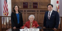 Alabama Extension Director Eve Brantley and Interim 1890 Extension Administrator Majed Dweik both standing with Alabama Governor Kay Ivey seated prior to signing the Alabama Extension Week proclamation.