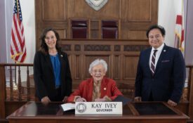 Alabama Extension Director Eve Brantley and Interim 1890 Extension Administrator Majed Dweik both standing with Alabama Governor Kay Ivey seated prior to signing the Alabama Extension Week proclamation.
