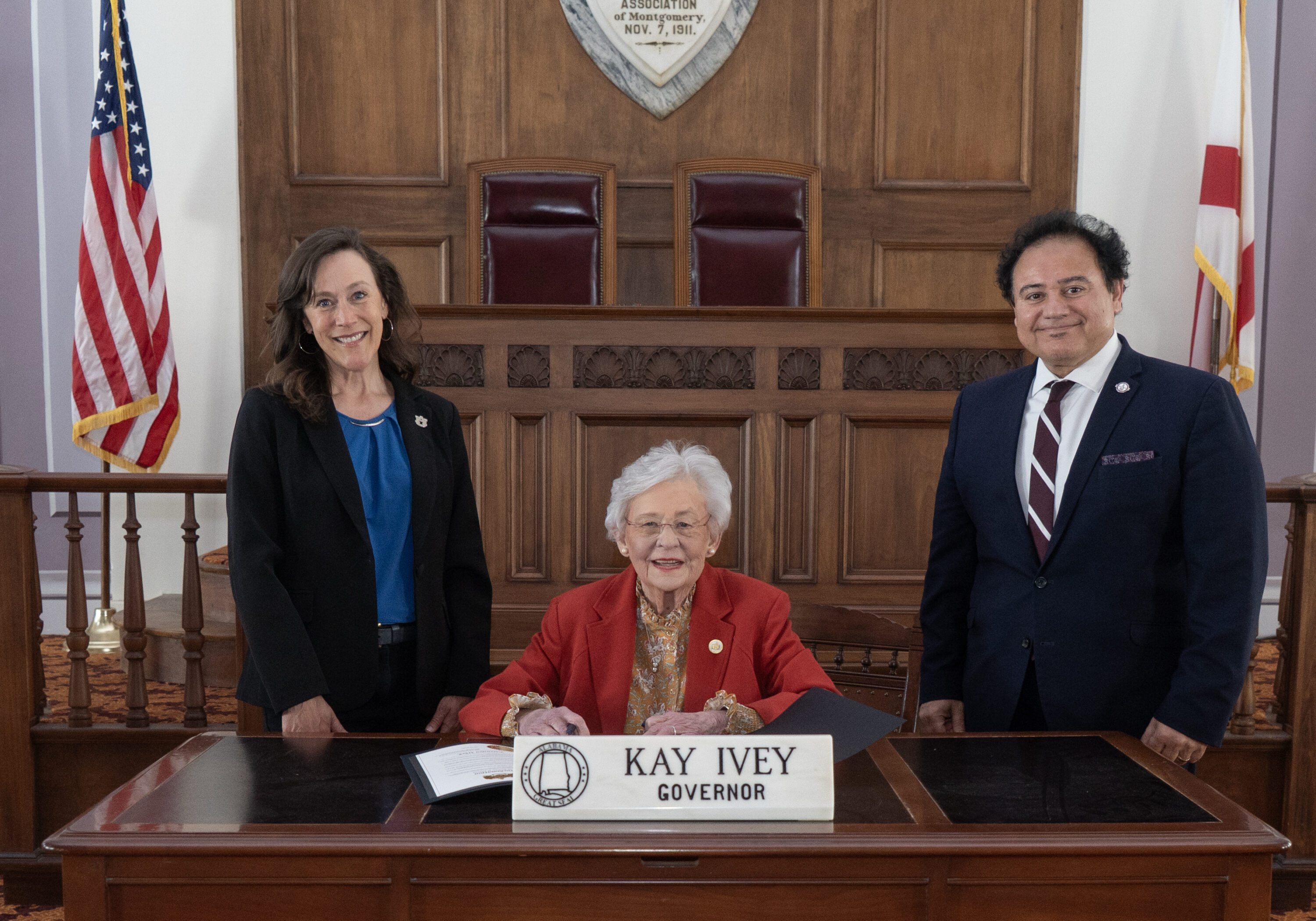 Alabama Extension Director Eve Brantley and Interim 1890 Extension Administrator Majed Dweik both standing with Alabama Governor Kay Ivey seated prior to signing the Alabama Extension Week proclamation.