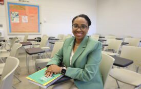 A photo of Portia Johnson in a classroom. She is wearing a light green suit while sitting in a desk.