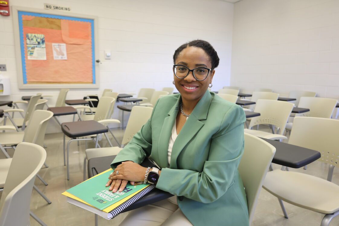 A photo of Portia Johnson in a classroom. She is wearing a light green suit while sitting in a desk.