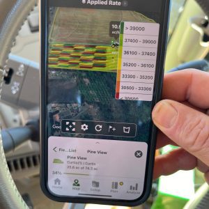 A person holding a smart phone with an app that shows the variable seeding rate on an app.