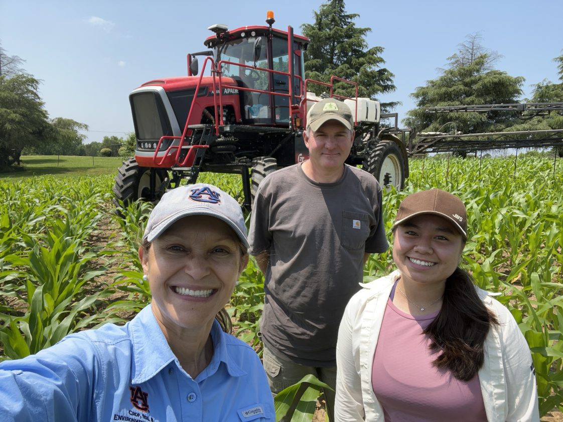 A group of people posing for a selfie while standing in a corn field.