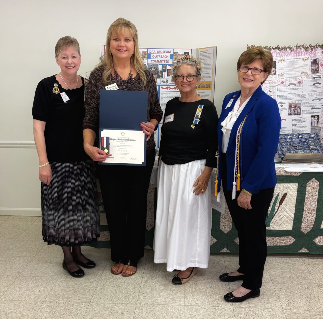 Three members of a local DAR chapter present an award to Alabama Extension's Lee Ann Clark.