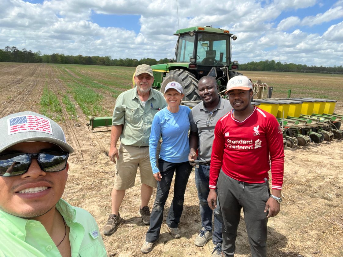 A group of people posing for a selfie while standing in a corn field.