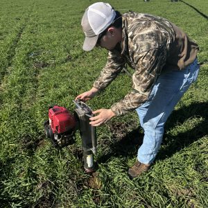 A man taking a core sample for soil textural analysis.