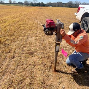 A man taking a soil core sample for soil textural analysis at a depth of 24 inches.