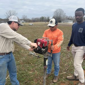 Three men taking a soil sample in a corn field.