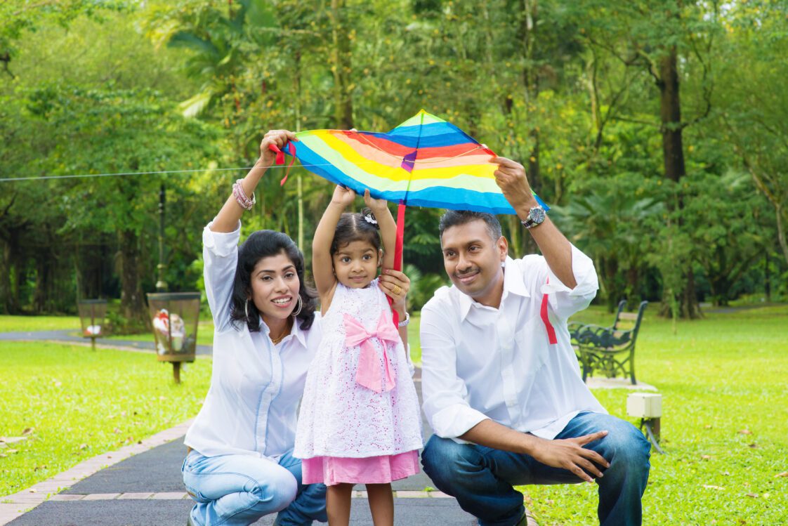 A mother, daughter and father outside holding up a kite.