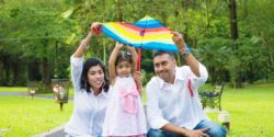 A mother, daughter and father outside holding up a kite.