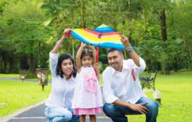 A mother, daughter and father outside holding up a kite.