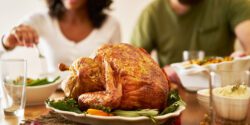 A closeup of a Thanksgiving turkey on a dinner table with a man and woman seen in the background.