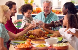 Multi-generation family celebrating Thanksgiving at home, eating a meal together.