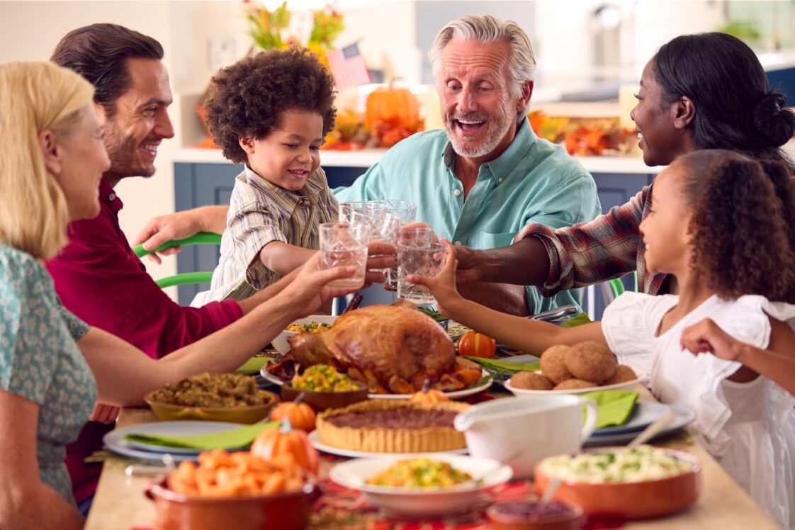 Multi-generation family celebrating Thanksgiving at home, eating a meal together.