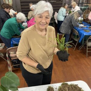 A woman holding a plant during a gardening workshop.