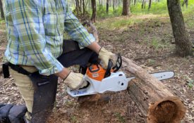 A man demonstrating proper chainsaw safety while cutting a log.