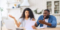 A man and woman sitting a a kitchen table reviewing financial paperwork.