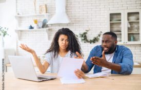 A man and woman sitting a a kitchen table reviewing financial paperwork.