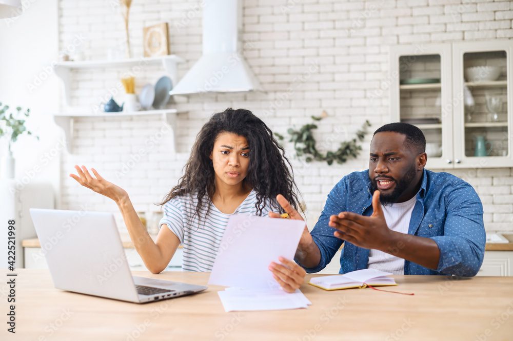 A man and woman sitting a a kitchen table reviewing financial paperwork.