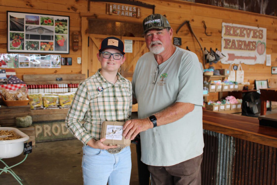 Eleven-year old Desper Dobbs sells his Desper's Dozen brand eggs at Reeves Peach Farm in Hartselle. Desper is pictured with farm owner Mike Reeves.
