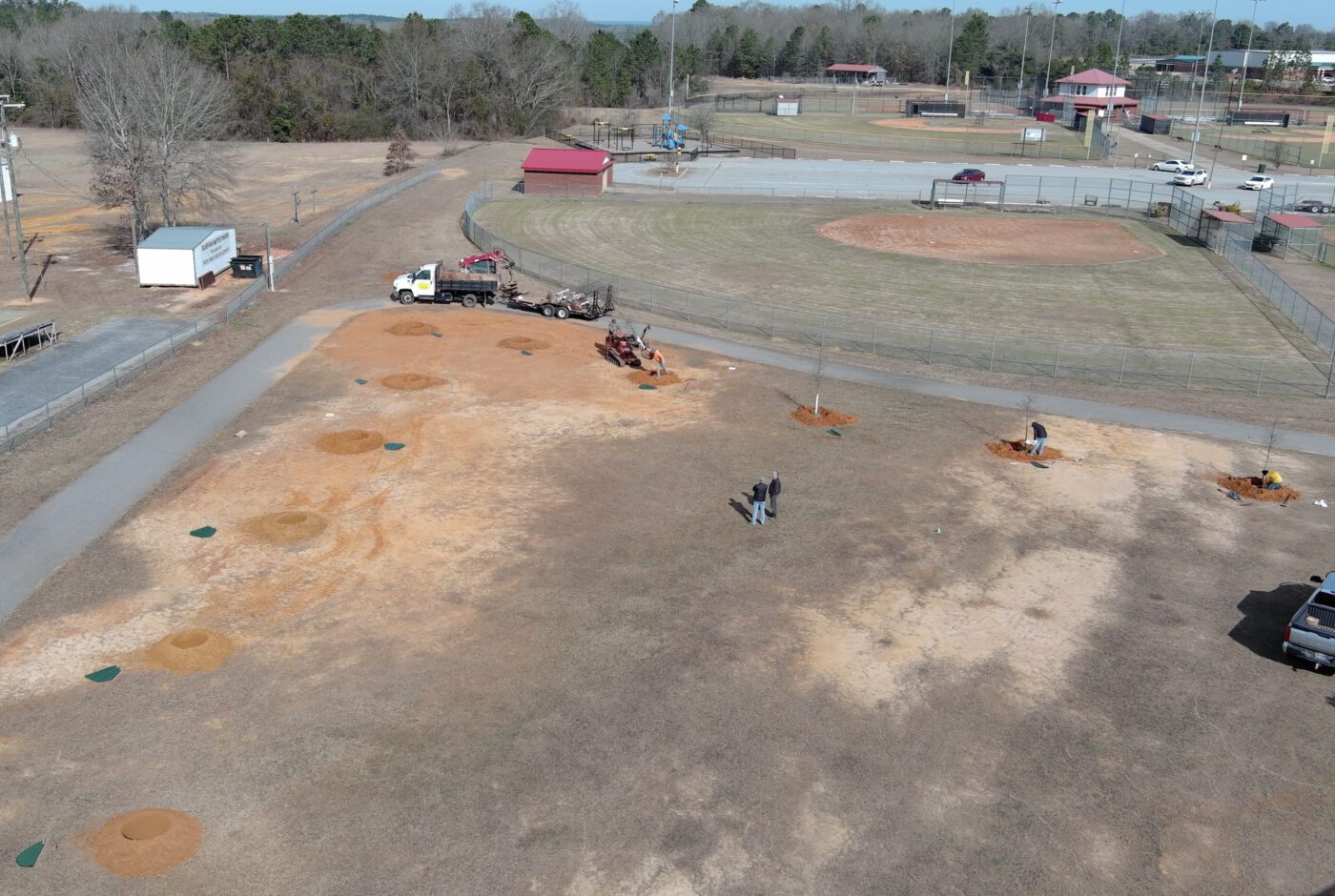 A drone shot of an empty park where trees have been planted along walkways to provide shade.
