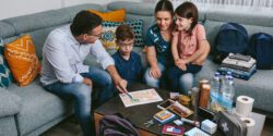 A family sitting on a couch around a coffee table that is stocked with emergency supplies. They are reviewing an emerency plan.