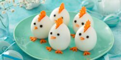 A plate of boiled eggs where cut carrots and peppercorns added to the eggs make them look like baby chicks for Easter.