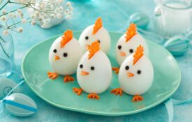 A plate of boiled eggs where cut carrots and peppercorns added to the eggs make them look like baby chicks for Easter.