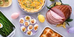An overhead image of a table with Easter decorations and food, including ham and eggs.