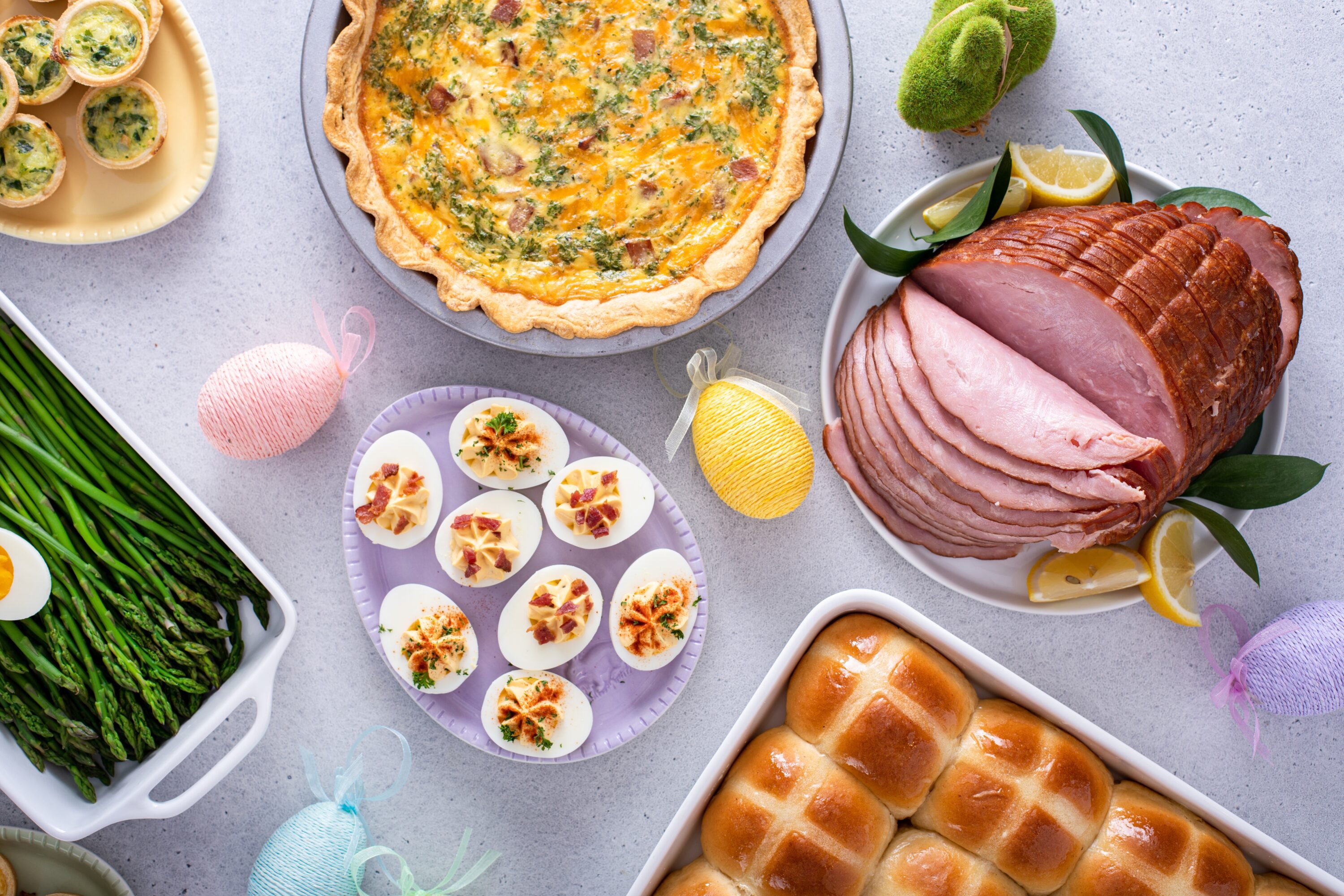 An overhead image of a table with Easter decorations and food, including ham and eggs.