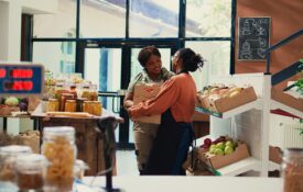 Two women standing and talking in a small-business grocery store.