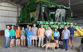 A group of Alabama Extension agents and specialists with their Australian hosts standing in front of a piece of farm machinery.