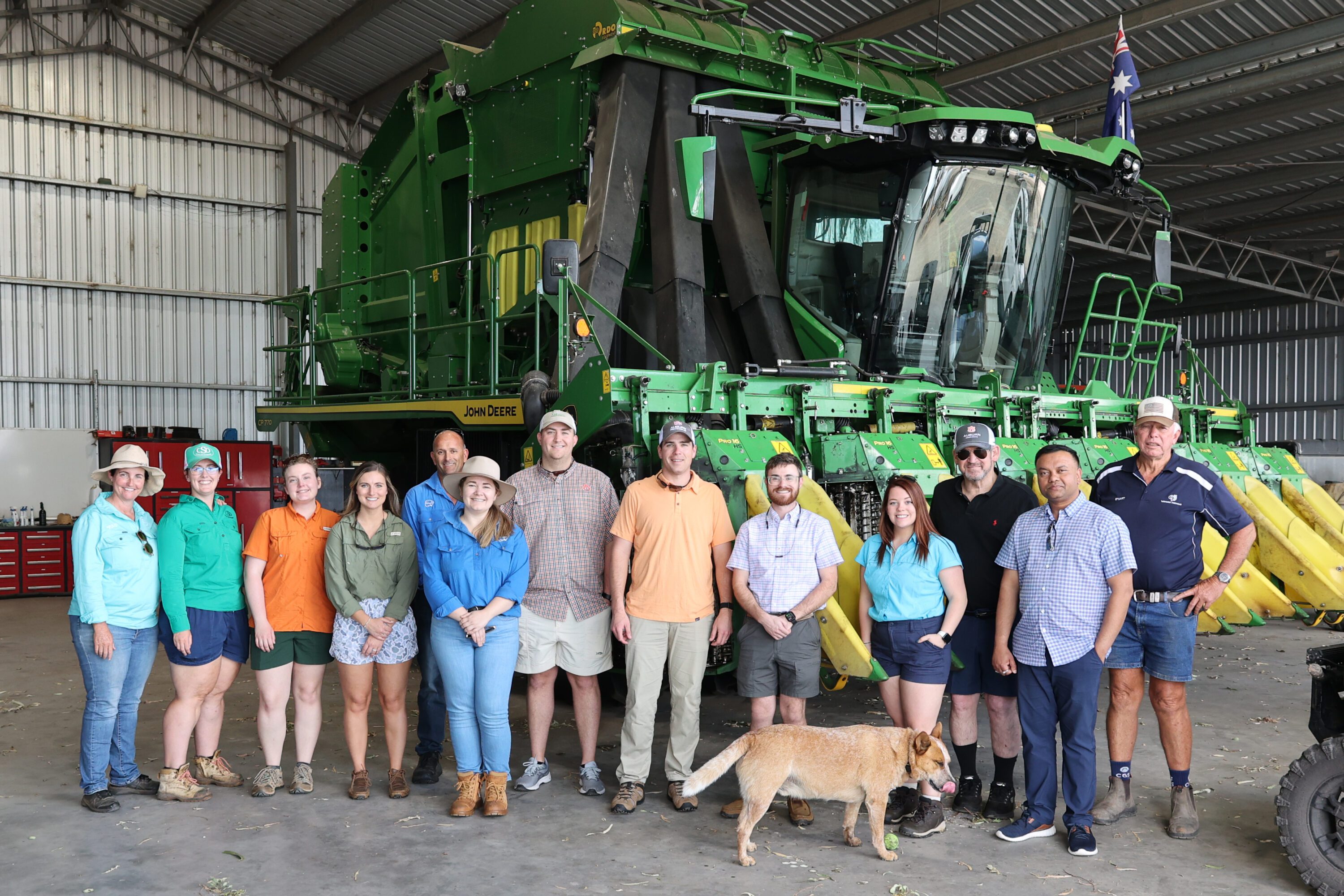 A group of Alabama Extension agents and specialists with their Australian hosts standing in front of a piece of farm machinery.