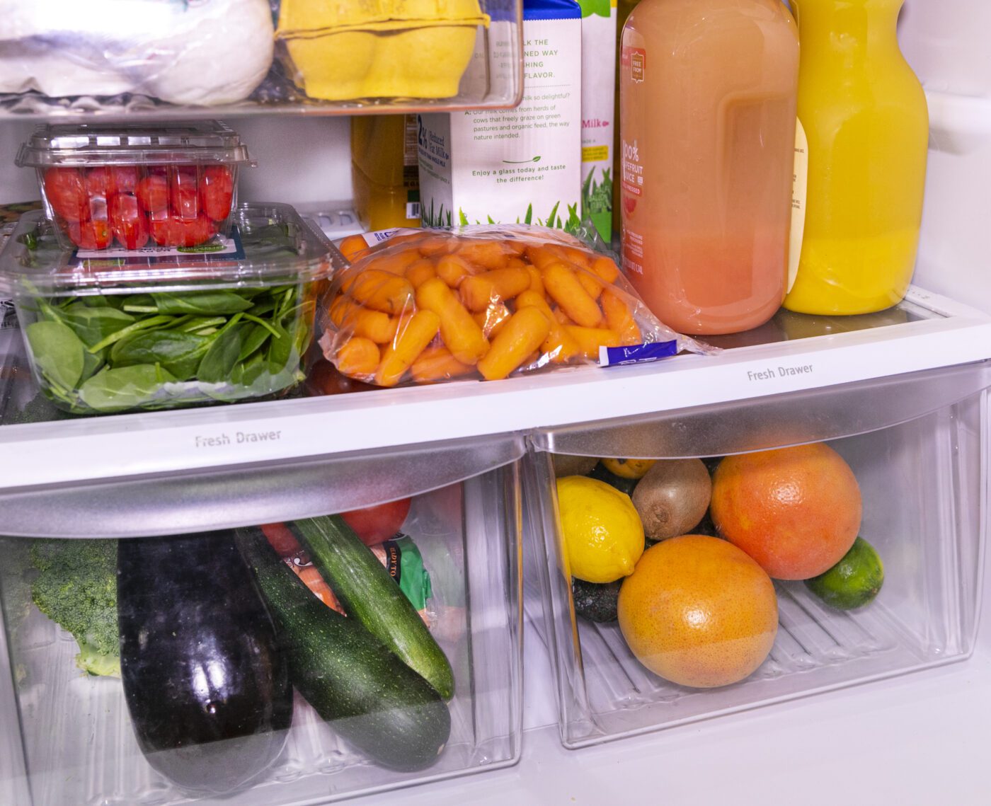 The inside of a refrigerator filled with fruits, vegetables, eggs and juices.