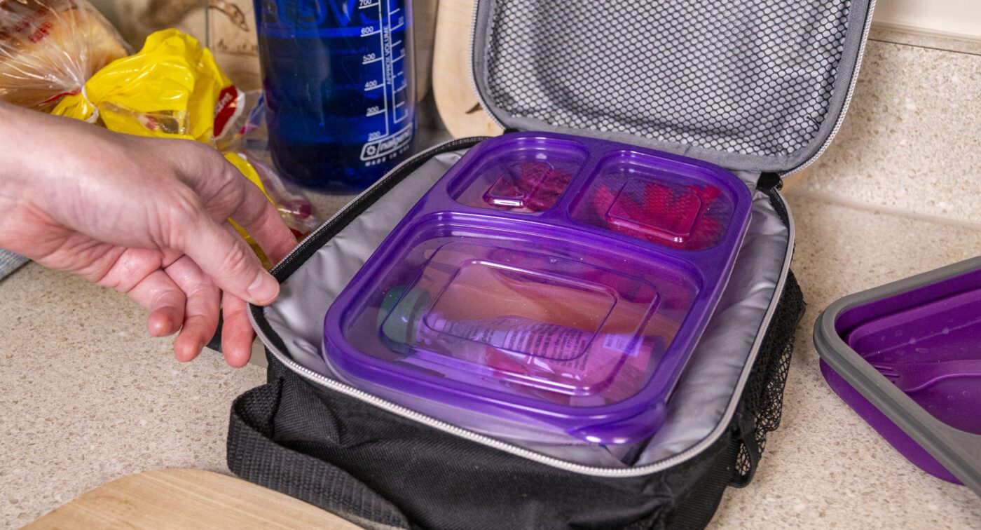A lunch packed in a container and being placed inside an insulated lunchbox.