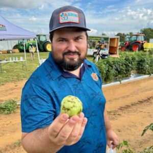 Figure 4. Paulo Cremonez with a tomato infected by tomato spotted wilt virus.