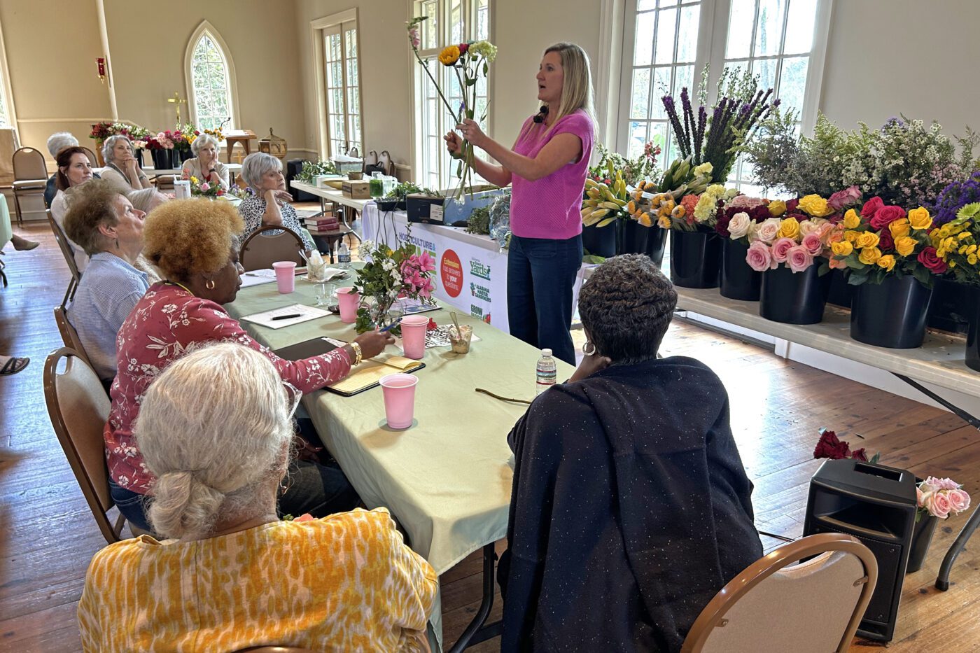 Alabama Extension Home Horticulture Agent Mallory Kelley explains the hands-on demonstration during the floral design workshop as a crowd looks on.