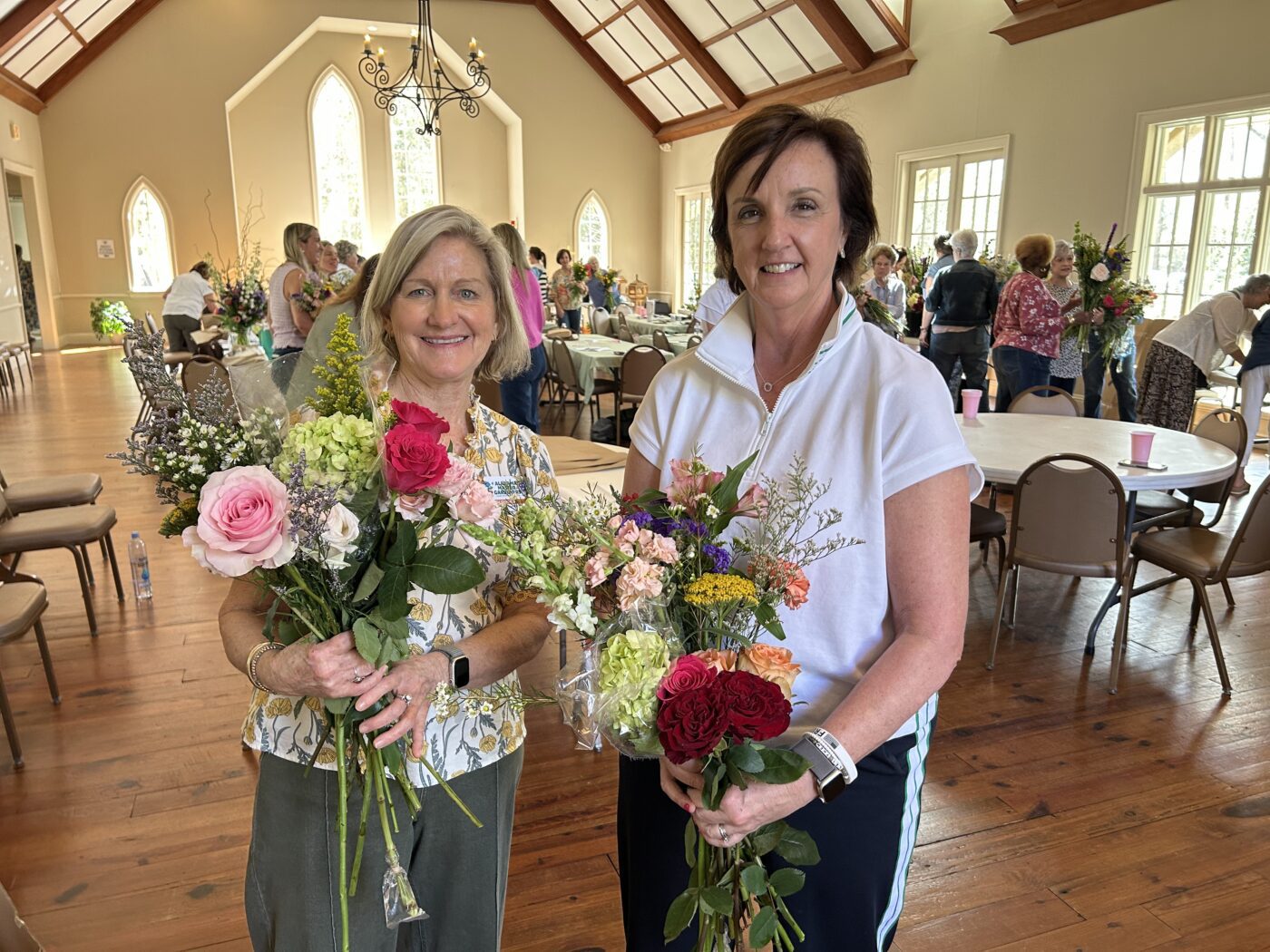 Two women stand with their flower arrangements.