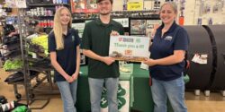 A group of three people inside a Tractor Supply store holding a sign that reads Thank you 4-H.