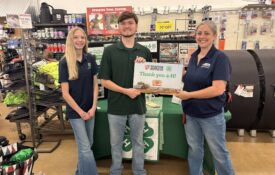 A group of three people inside a Tractor Supply store holding a sign that reads Thank you 4-H.