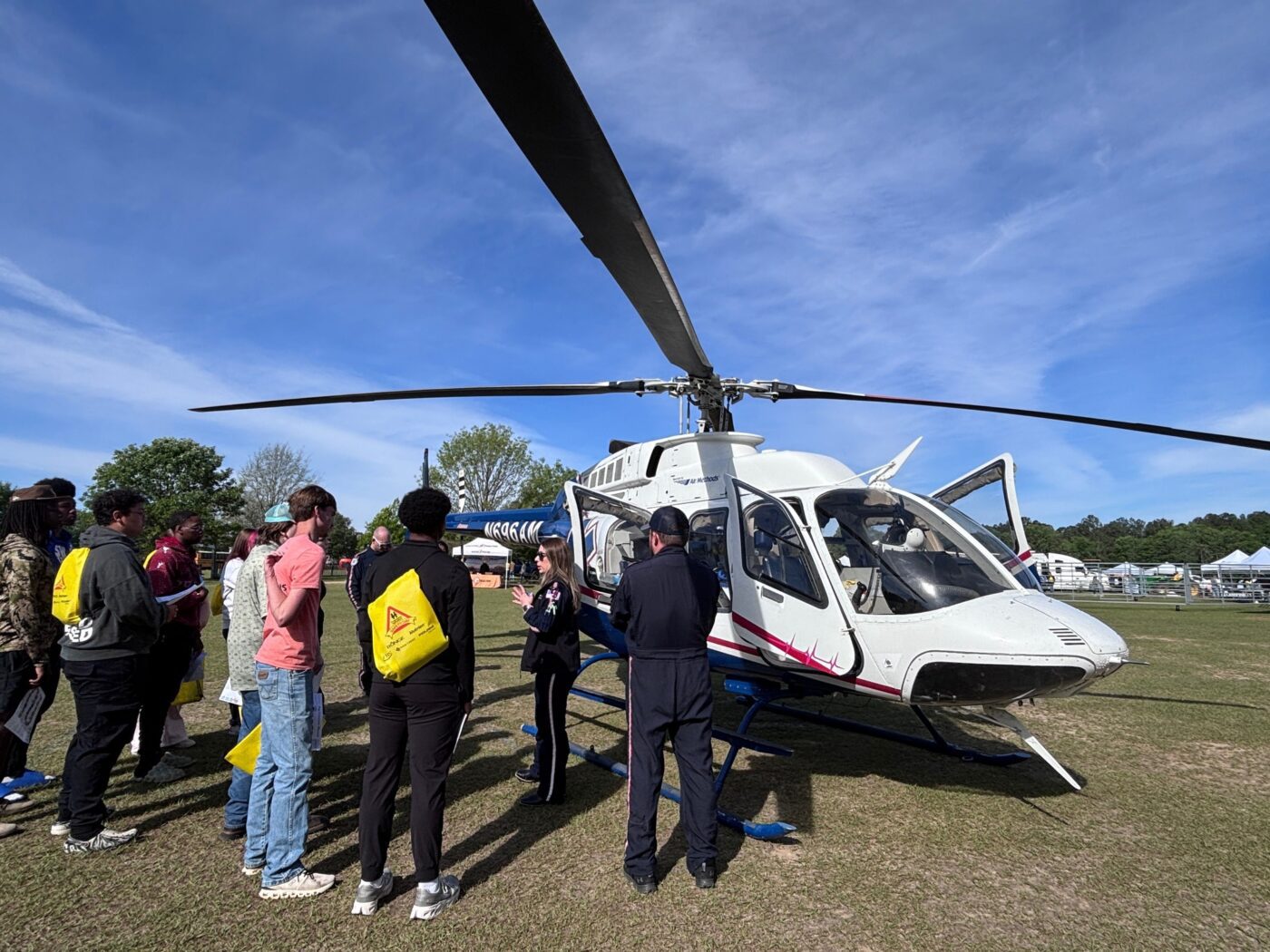 Emergency responders with a group of students standing outside a helicopter.