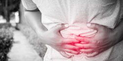 A young man holding his stomach as he was feeling sick.